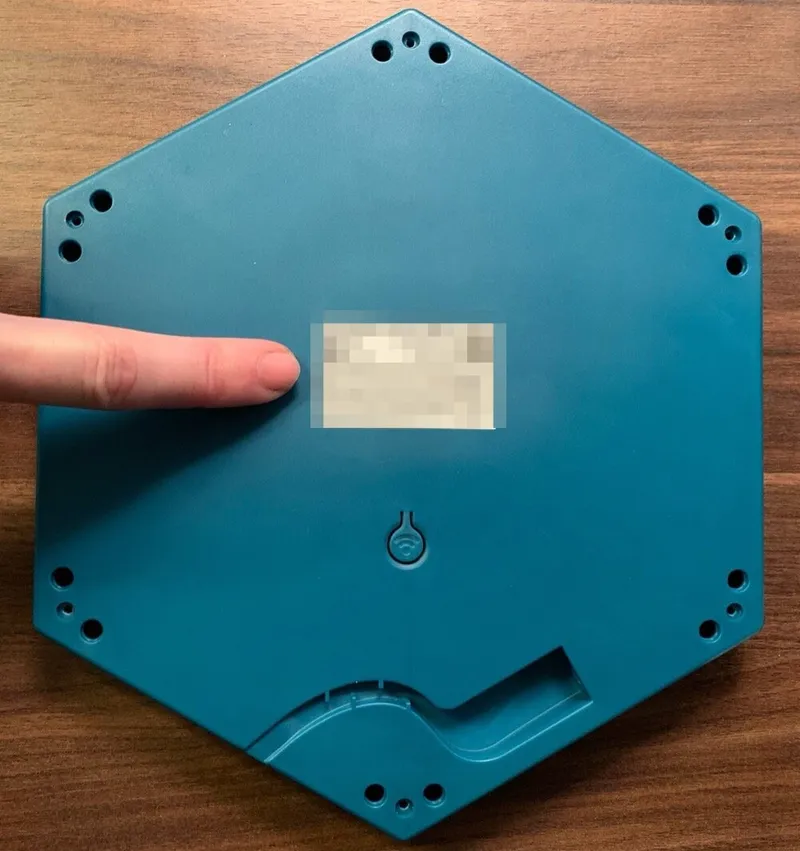 The bottom of a Connect Base, with a finger pointing at the product label in the center. The label is blurred in this photo.