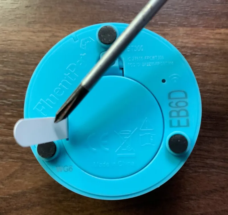 The bottom of a Connect Button with the white battery tab sticking out from under the battery cover.